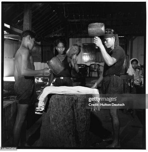 Textile workers use mallets to soften the material of sarongs at a textile factory in Jakararta.