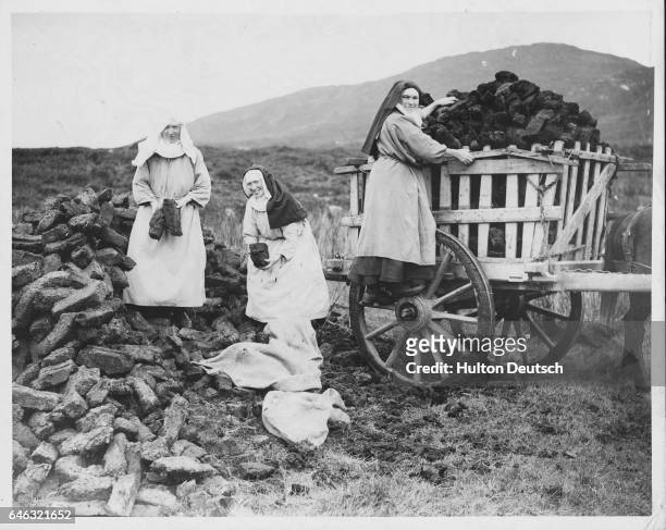 Three nuns from Kylemore Abbey, Connemara, harvest peat to provide fuel during the winter. Here they load the peat into their cart.