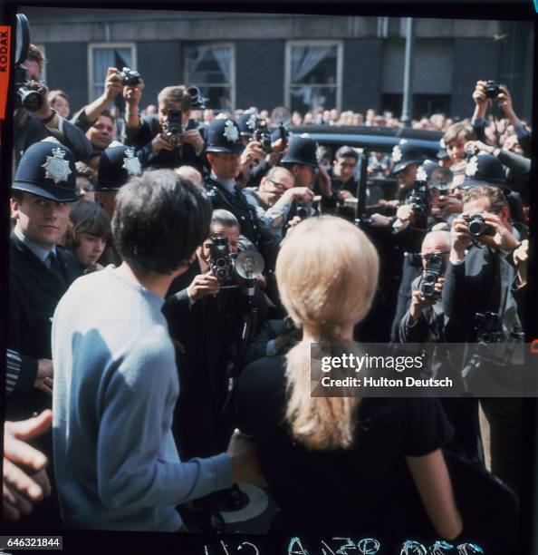 British photographer David Bailey and actress Catherine Deneuve are surrounded by press photographers as they leave St. Pancras after their wedding.