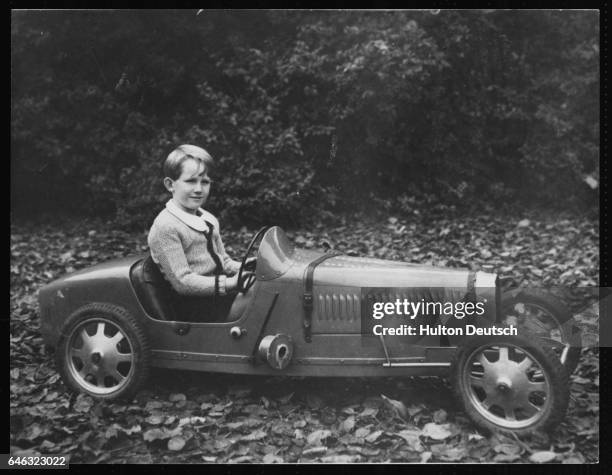 Crown Prince Baudouin, son of King Leopold of Belgium tries out his model automobile in the grounds of the Royal Palace at Laeken, Belgium, 1938