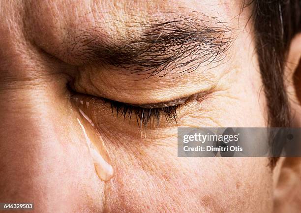 man crying, close-up of eye and tear - träne stock-fotos und bilder