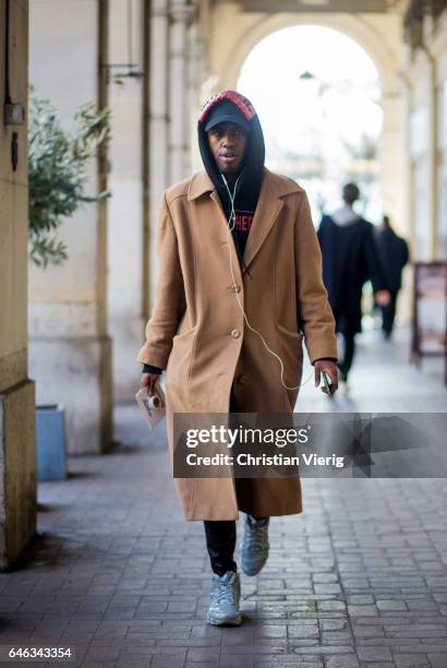 Guest wearing a beige coat, navy hoody, flex cap outside Anrealage on February 28, 2017 in Paris, France.