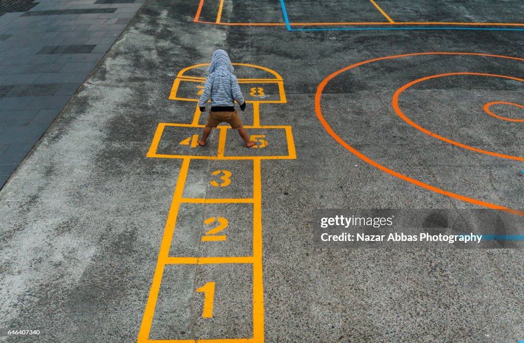 Kid Playing Hopscotch in Playground.