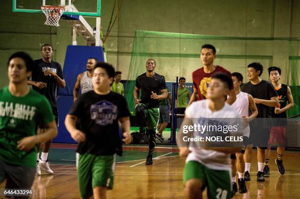 This picture taken on January 24, 2017 shows Cameroon's Benoit Mbala doing warm ups with other student players during a basketball practice session...