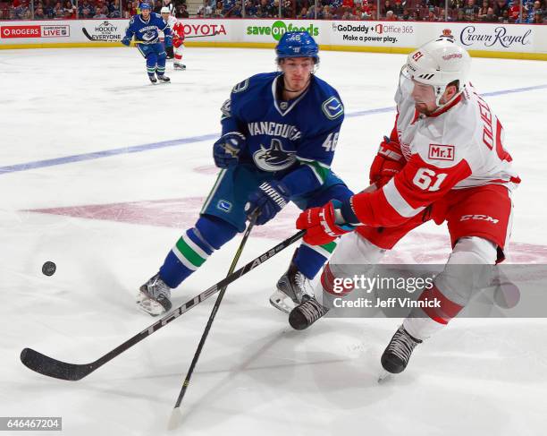 Jayson Megna of the Vancouver Canucks checks Xavier Ouellet of the Detroit Red Wings during their NHL game at Rogers Arena February 28, 2017 in...