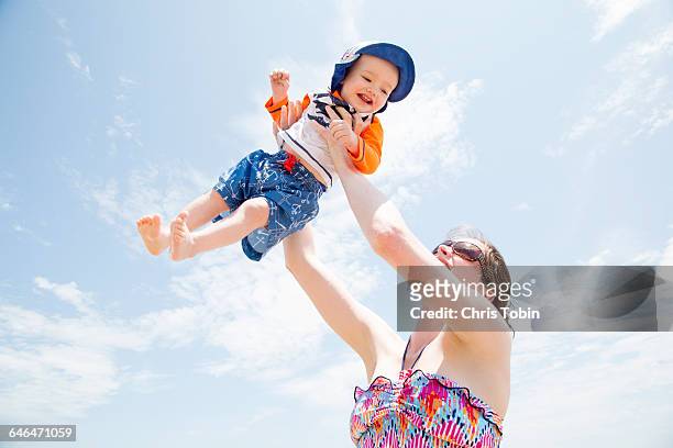 woman at beach lifting toddler up into air - ocean city maryland stock pictures, royalty-free photos & images