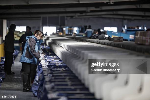 Workers stand next to an automatic package sorting machine at a ZTO Express Inc. Sorting facility in Shanghai, China, on Friday, Feb. 10, 2017....