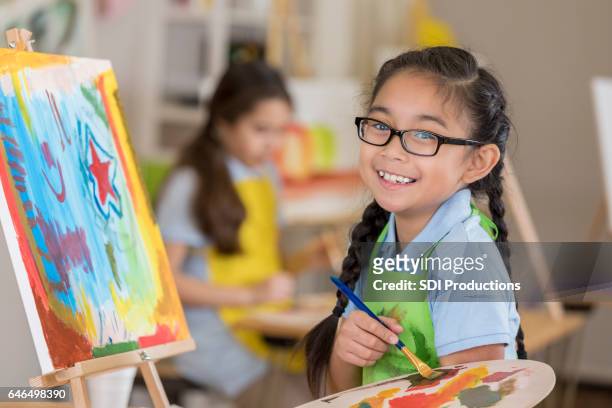 gioiosa giovane studentessa d'arte dipinge in uno studio - dipinto foto e immagini stock
