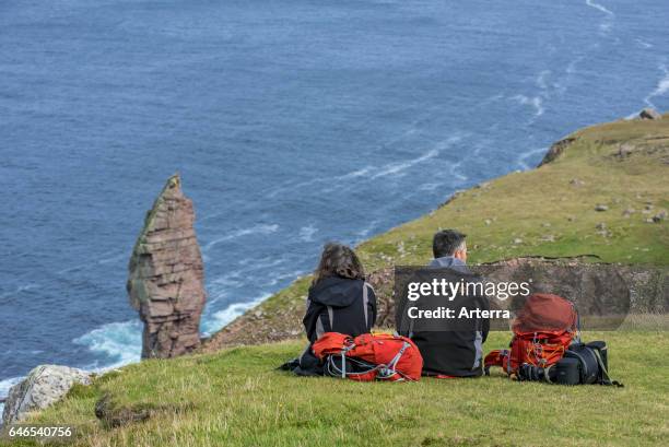 Walkers resting near the Old Man of Stoer, 60 metres high sea stack of Torridonian sandstone at the Point of Stoer in Sutherland, Scottish Highlands,...