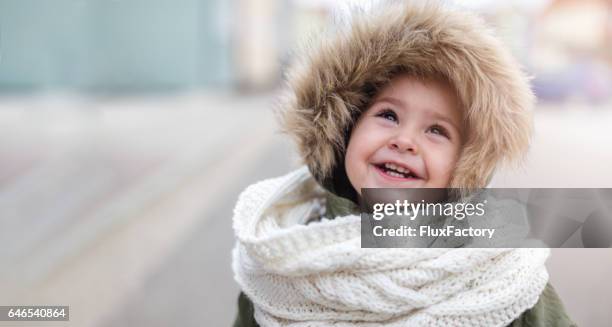 cute baby girl in winter jacket and scarf looking up - winter baby stock pictures, royalty-free photos & images