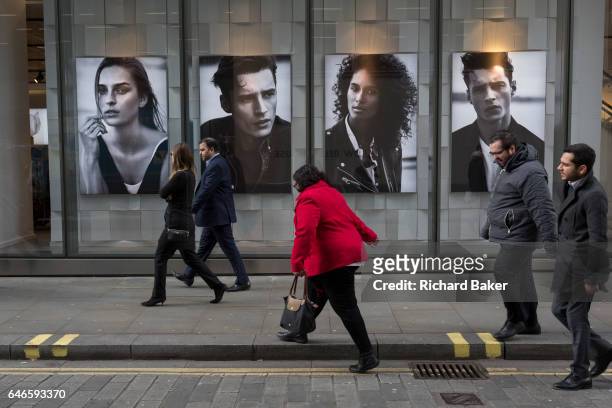 Passers-by walk along the street, outside an H&M retail shop, on 16th February 2017, in the City of London, England.