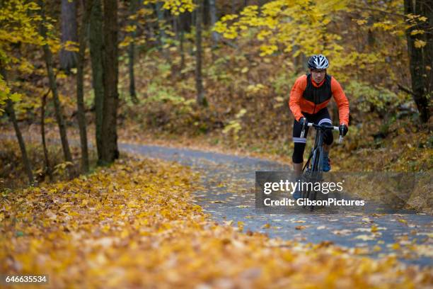 a man rides along a quiet country lane in british columbia, canada in autumn. - sportsperson stock pictures, royalty-free photos & images