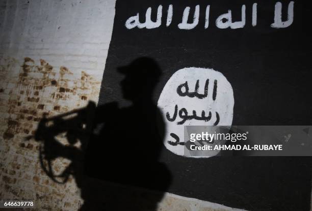 Member of the Iraqi forces walks past a mural bearing the logo of the Islamic State group in a tunnel that was reportedly used as a training centre...