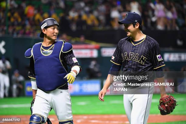 Pitcher Tomoyuki Sugano and Catcher Seiji Kobayashi of Japan talk while walking to the dugout after the bottom of the third inning during the SAMURAI...