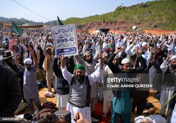 Pakistani Muslims raise their hands as they shout slogans as they gather outside the tomb of Mumtaz Qadri, who was hanged in February 2016 for the...