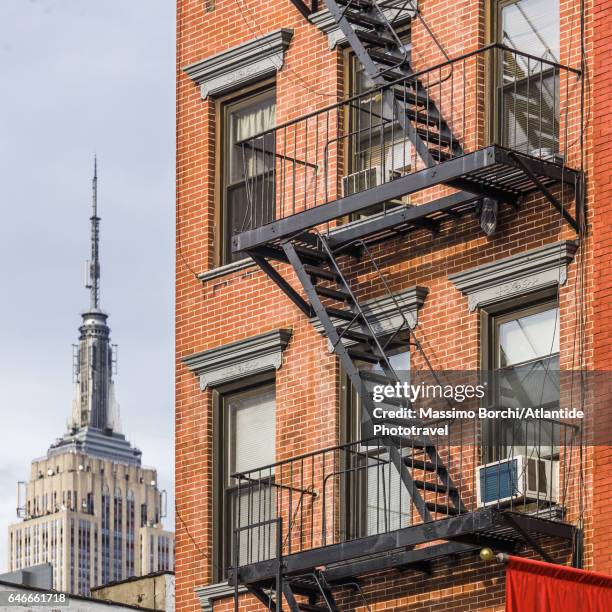 manhattan, chelsea, typical building and the empire state building on the background - new york empire state building stock pictures, royalty-free photos & images