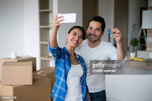 couple taking a selfie holding keys to their new house - move to new place stock pictures, royalty-free photos & images