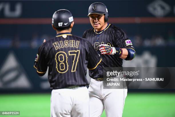 Designated hitter Seiichi Uchikawa of Japan high fives with coach Toshihisa Nishi after hitting a single in the top of the seventh inning during the...