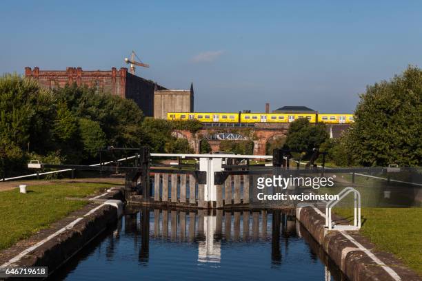 merseyrail electric train passing leeds liverpool canal at stanley dock - leeds canal stock pictures, royalty-free photos & images