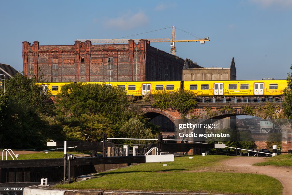 Merseyrail electric train passing Leeds Liverpool canal at Stanley Dock