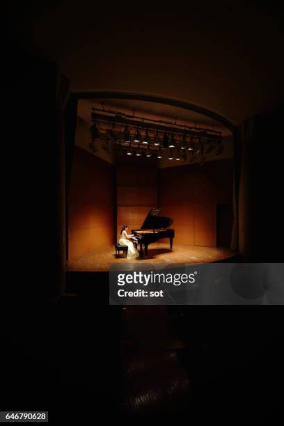 female pianist playing grand piano at concert hall - pianist stock pictures, royalty-free photos & images