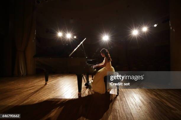 female pianist playing grand piano at concert hall stage - klassische musik stock-fotos und bilder