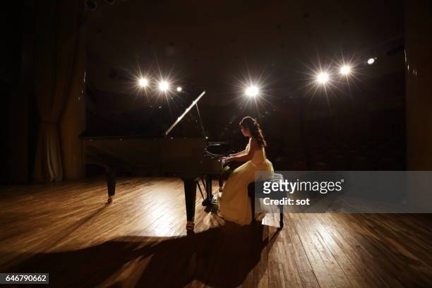 female pianist playing grand piano at concert hall stage - concert hall stage stock pictures, royalty-free photos & images