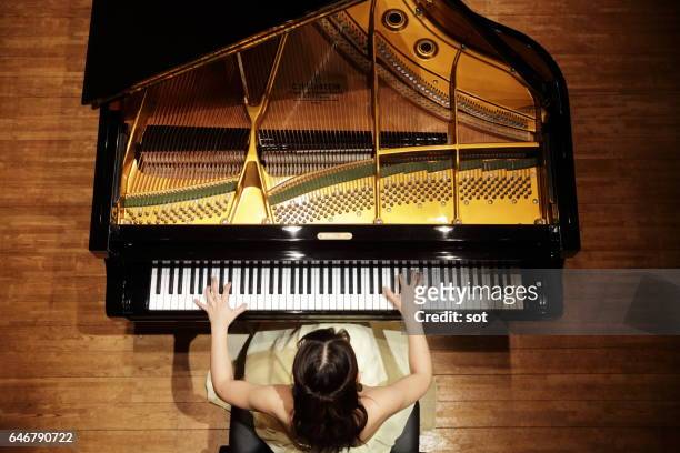 female pianist playing grand piano at concert hall stage,aerial view - piano stock pictures, royalty-free photos & images