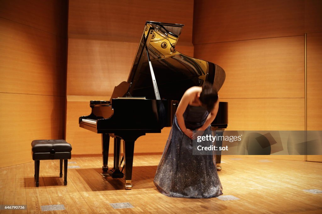 Female pianist bowing on concert hall stage