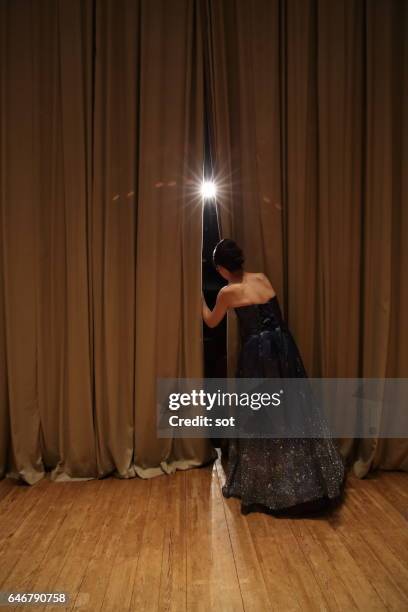 female peeking through curtains of concert hall stage,rear view - rideau de scène photos et images de collection