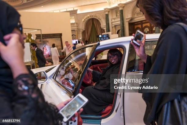 Women pose behind the wheel of a car at a luxury goods fair in Riyadh, Saudi Arabia, on March 13, 2015.