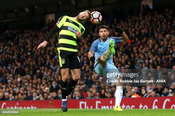 Martin Cranie of Huddersfield Town and Sergio Aguero of Manchester City compete during the Emirates FA Cup Fifth Round replay match between...