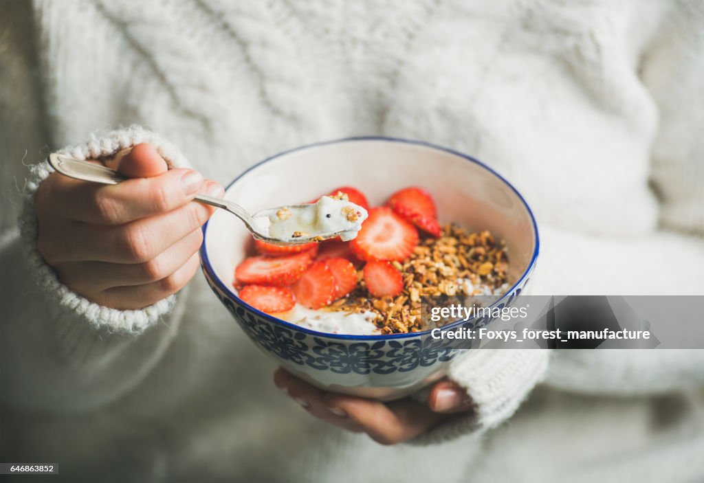 Healthy breakfast yogurt, granola, strawberry bowl in woman's hands