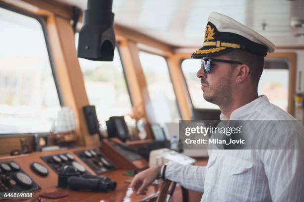 joven capitán dirección en bote - boat captain fotografías e imágenes de stock