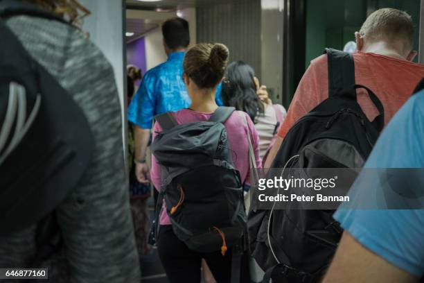 passengers carrying bags in airbridge boarding aircraft, rear view, faces obscured - passenger boarding bridge stock-fotos und bilder