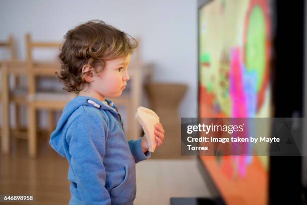 toddler watching tv with a sandwich - child animated watching stock-fotos und bilder