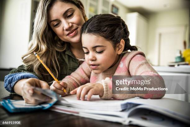mother and daughter (7 yrs) doing homework - werkboek stockfoto's en -beelden