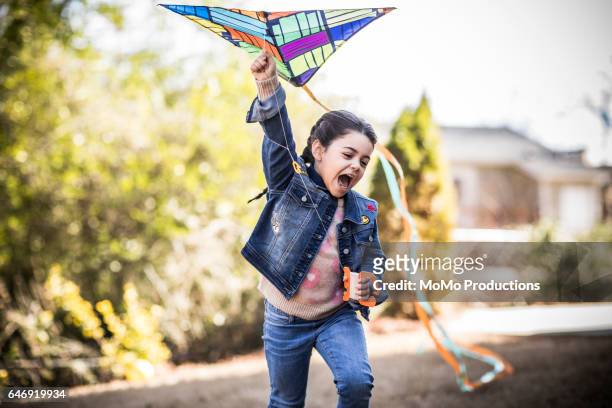 girl (7yrs) flying kite in backyard - kite toy stock-fotos und bilder
