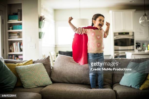 girl (7yrs) wearing superhero cape, indoors - child strong stock-fotos und bilder