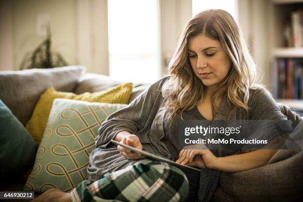 woman using tablet on couch - digital business relationship stock pictures, royalty-free photos & images