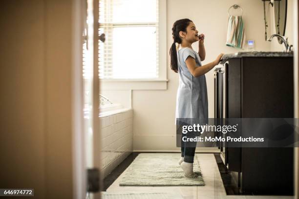 girl on tiptoes brushing teeth in bathroom - tip toeing stock pictures, royalty-free photos & images