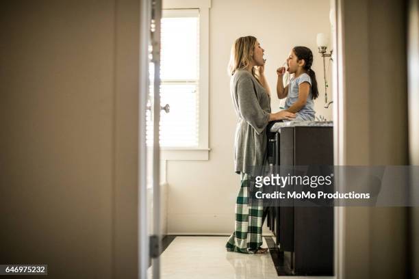 mother and daughter (7yrs) brushing teeth in bathroom - tandpasta stockfoto's en -beelden