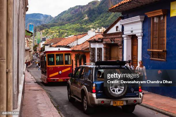 bogotá colombia - vehicular traffic moves down a narrow street in the historic la candelaria district, in the andean capital city - sports utility vehicle stock pictures, royalty-free photos & images