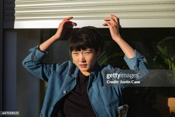 woman opening her studio blinds - koreanischer abstammung stock-fotos und bilder