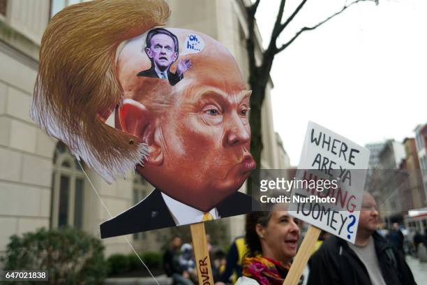 Artist Carla Krash holds a Trump-protest sign that includes a moving hairpiece as she joins a small group of protestors outside US Customs and Border...