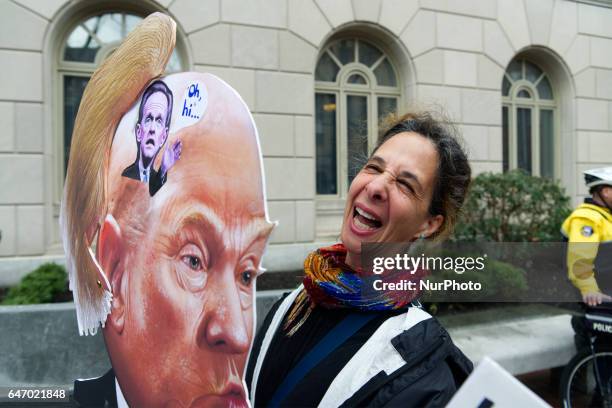 Artist Carla Krash holds a Trump-protest sign that includes a moving hairpiece as she joins a small group of protestors outside US Customs and Border...