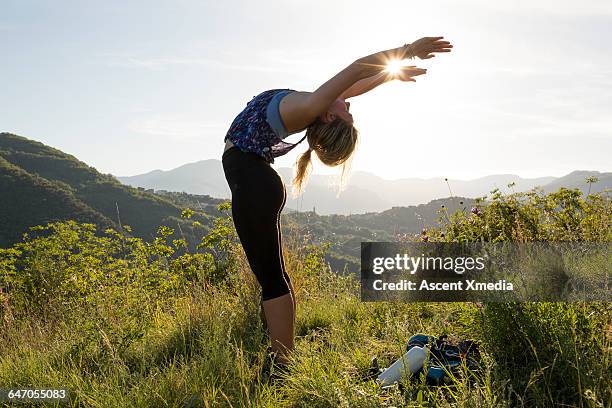 female hiker performs back stretch in meadow - bending over backwards stock pictures, royalty-free photos & images