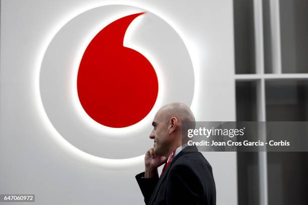 Congress attendant speaks on his smartphone in front of the Vodafone company logo on their stand during the Mobile World Congress on March 1, 2017 in...