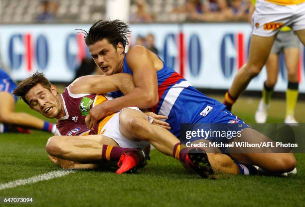 Ryan Bastinac of the Lions is tackled by Tom Boyd of the Bulldogs during the AFL 2017 JLT Community Series match between the Western Bulldogs and the...