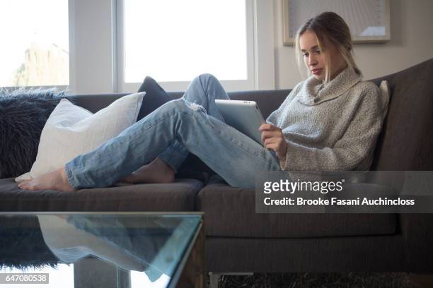 woman on couch with laptop - grey jeans stock pictures, royalty-free photos & images